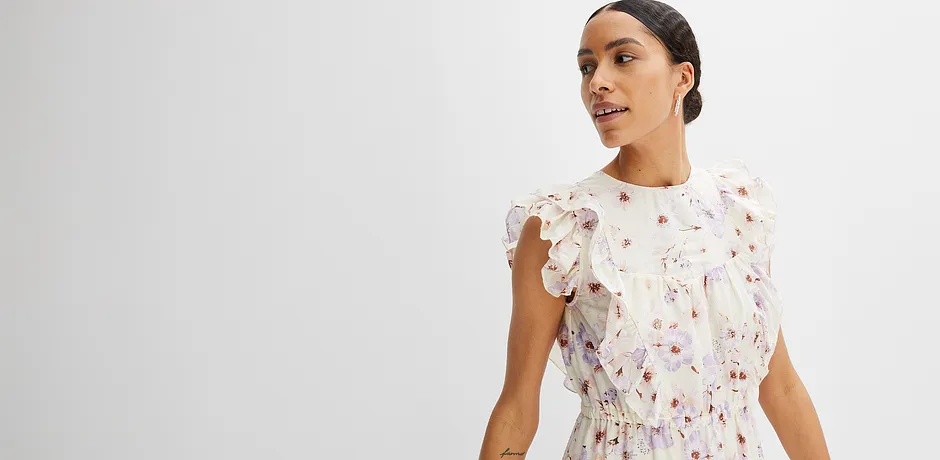 Zartes Sommerkleid mit Blumenmuster und Rüschenärmeln. Weiß mit rosa Akzenten, feminin und verspielt.