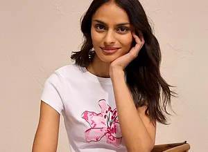Das weiße T-Shirt mit rosa Blumenmotiv strahlt Frische und Leichtigkeit aus.