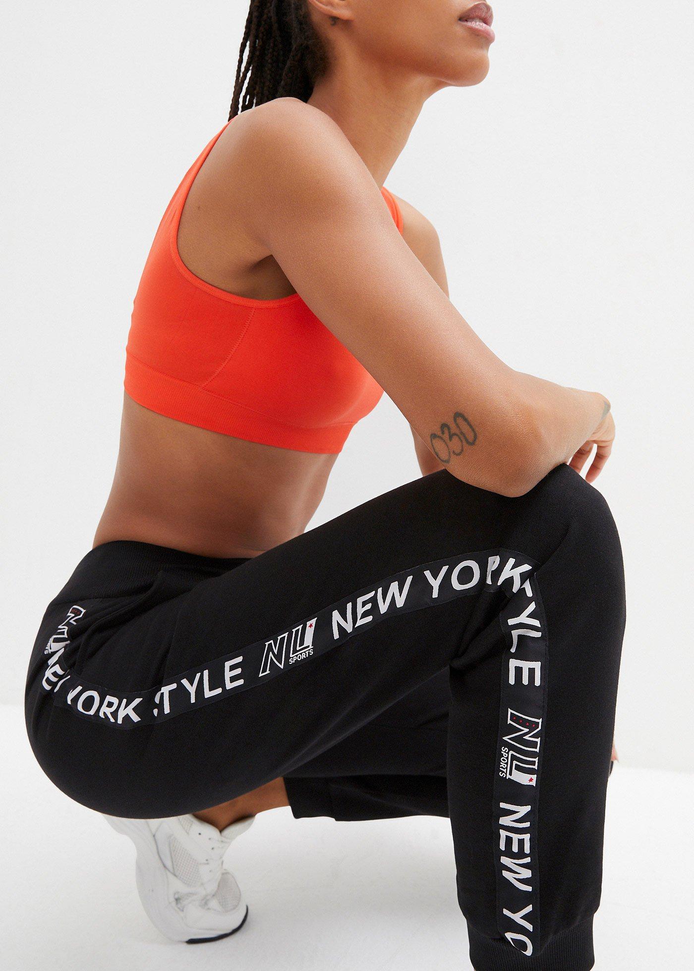 Spodnie dresowe ze ściągaczem w talii i u dołu nogawek z napisem - Bonprix